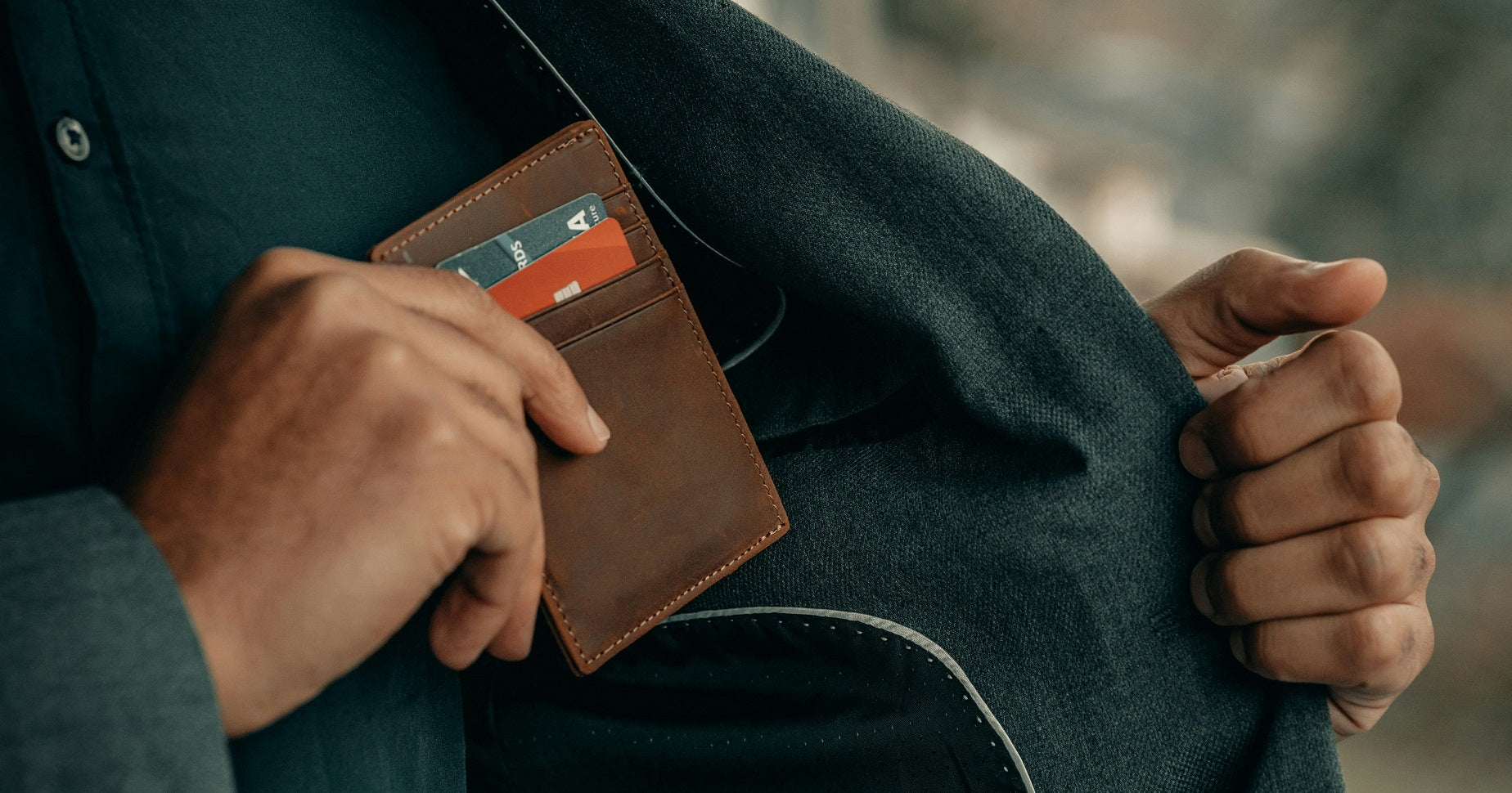 Das Foto zeigt, wie eine Person das Portemonnaie in der Innentasche der Jacke verstaut.