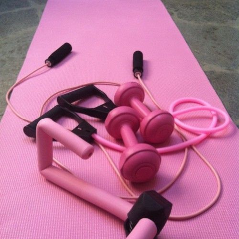 Weights and skipping rope on a pink gym mat