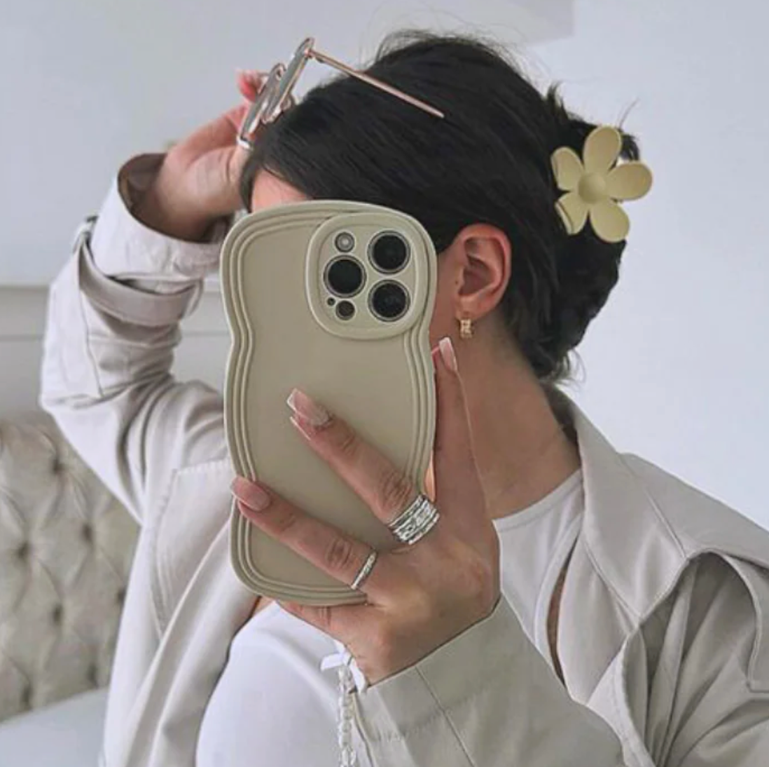 Person taking a selfie with a wavy phone case and floral hair accessory.