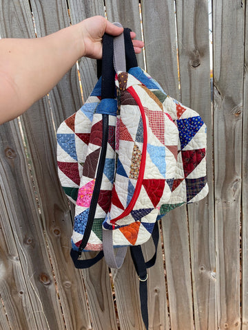 a hand holding up several vintage quilted crossbody bags