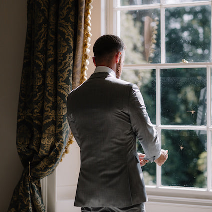 groom looking out of the window on wedding day