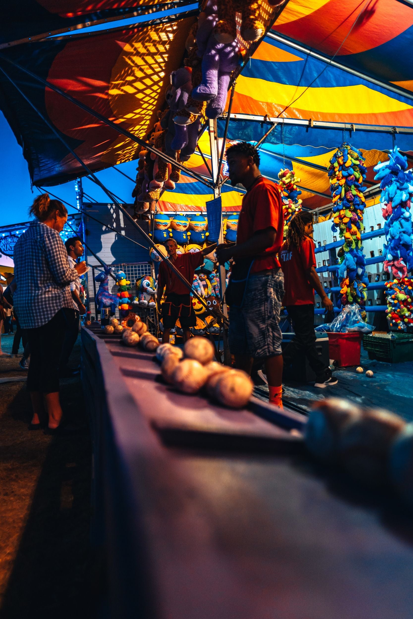 people playing ball toss game at county fair