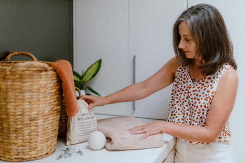 Women looks at CaliWoods Eco Wool Dryer Balls while folding towels