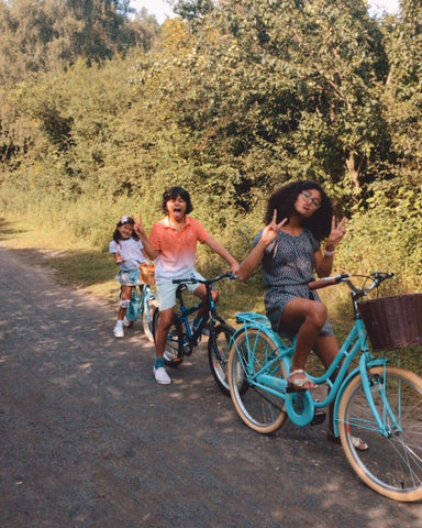 Drei Kinder schneiden Grimassen auf einem Fahrrad