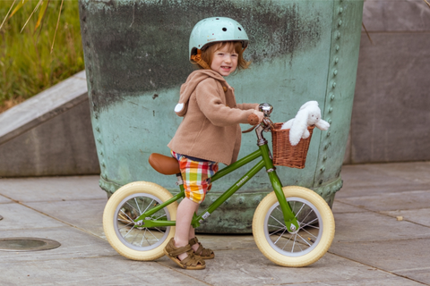 Boy on a green balance bike wearing a light blue helmet