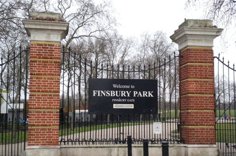 Entrance to Finsbury Park with a distinctive gate made of orange brick stones and black metal fencing.