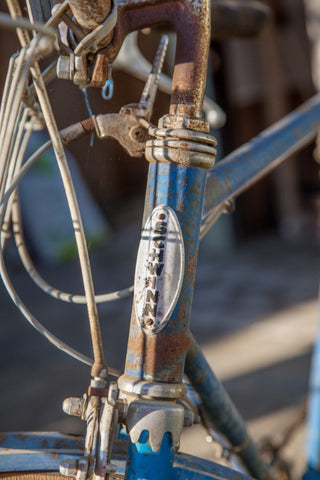 Rusty bike frame with peeling blue paint.