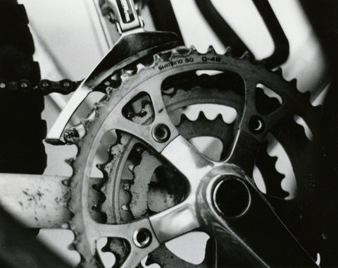 A close-up B&W image showcasing the intricate mechanics of bike gears, highlighting the chain, cassette, and derailleurs.