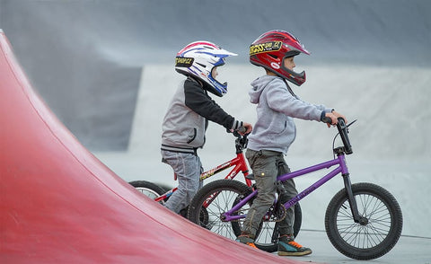 Two boys enjoying a BMX bike ride, wearing safety helmets for protection.