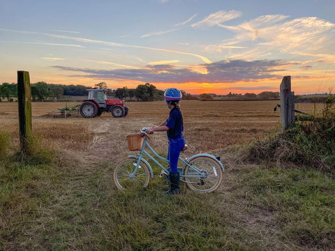 girl on bike in farmers field with a tractor