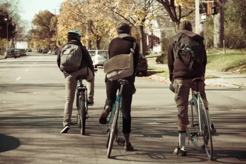 Back view of three men cycling with backpacks.