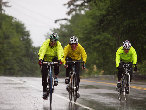 Cyclists participating in a local bicycle race amidst heavy rain with reflective rain jackets for visibility.