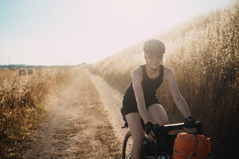 Une femme bikepacker à vélo par une chaude journée ensoleillée