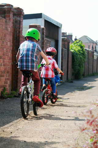 A photo of two kids cycling along the neighbourhood