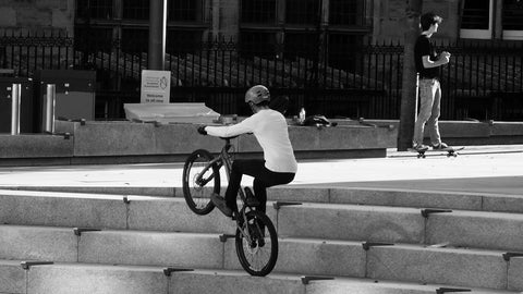 A young rider having fun, bunny hopping his bike up and down the steps by the side of the Bistro Square.