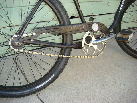 A black bike with a new tire, rim, and chains.