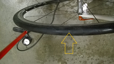 An arrow pointing the puncture in a tubeless bike tyre