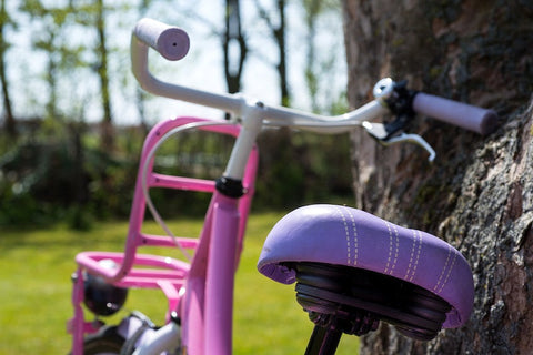 A kid's bicycle, featuring a pink frame and a purple saddle