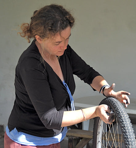 A woman fixing a bike wheel