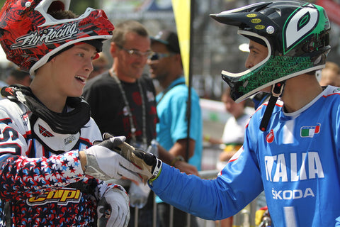 Young BMX riders in full gear, shaking hands with helmets on.
