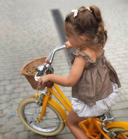 petite fille sur vélo d'équilibre jaune avec un panier