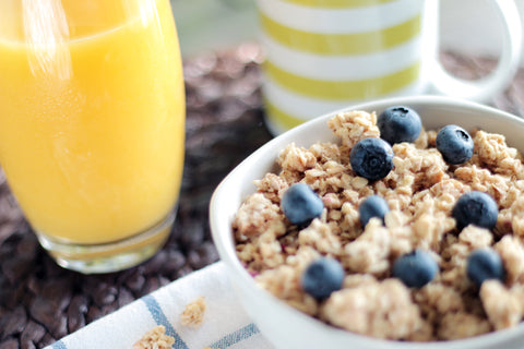 Bowl of oatmeal with berries beside glass of juice