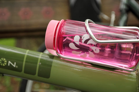 Pink water bottle secured in a metal holder on a bike