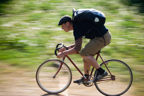 A cyclist pedalling downhill with a fixed-gear bike.