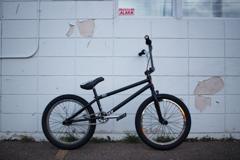 Compact BMX bike leaning against a plain wall.