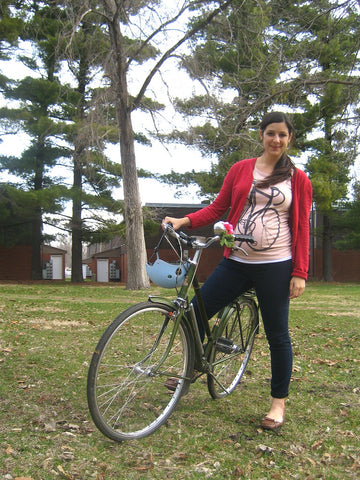 Pregnant woman joyfully posing on her bicycle during an outdoor ride.