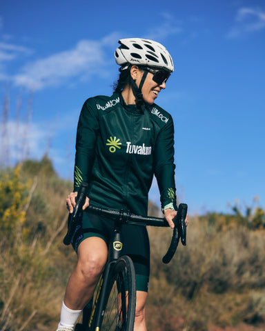 A woman in a green cycling jersey and helmet.