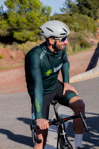 A man in a green cycling jersey and helmet.