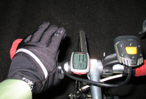 A rider’s perspective, featuring their left hand in a winter glove gripping the bike’s handlebar.