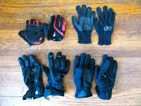 Four pairs of winter cycling gloves laid on a wooden floor