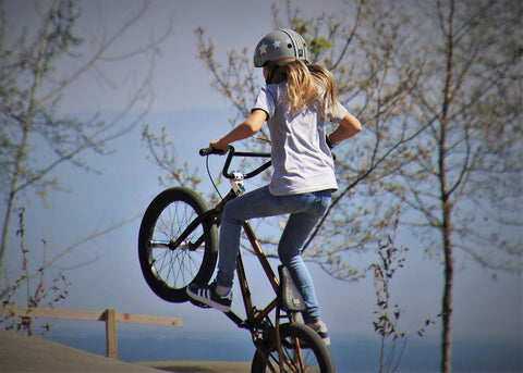 A young BMX rider captured mid-action, poised to execute a stunt.