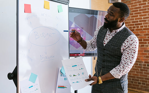 Man explaining budget charts in front of whiteboard