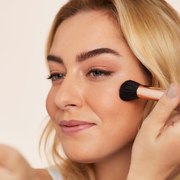 Woman applying jane iredale blush with brush