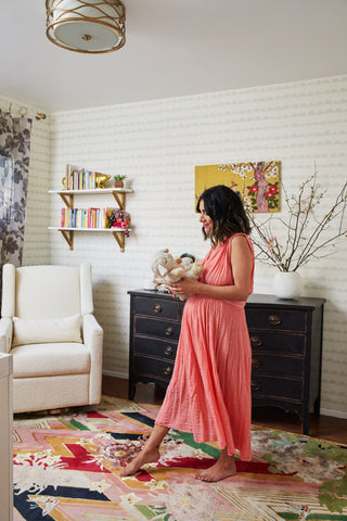 Annette Vartanian in her Vintage Maximalism nursery, which features the babyletto Kiwi Recliner in Ivory Boucle with a Gold base and a weathered black French Provincial from a flea market