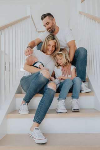 Josh and Heather pictured with their daughter Charlie and baby Asher in matching white tops and denim.