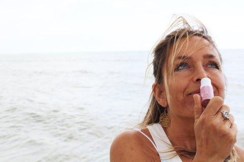 women sniffing aromatherapy love balm on a beach