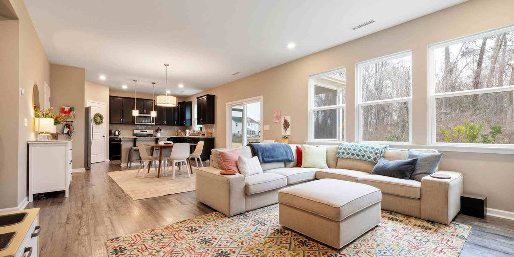 Image depicting an L-shaped sofa used as a room divider in an open floor plan, effectively separating the living room and kitchen areas. While the kitchen remains accessible and visible, the sofa provides a clear boundary and creates a cozy, defined living space. This photo illustrates how thoughtful furniture arrangement can serve multiple purposes, including acting as subtle room dividers to define distinct zones within a condo