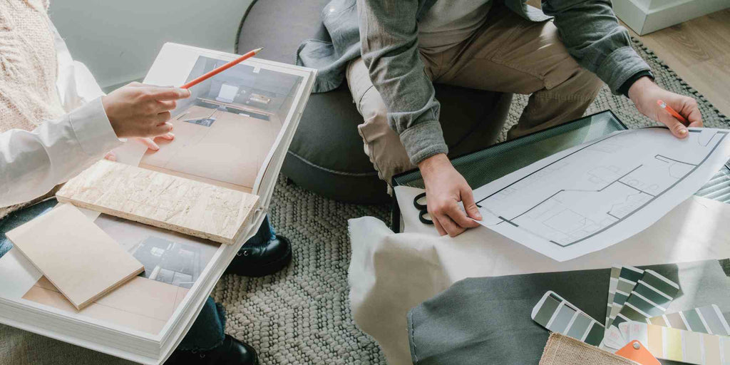 An image of an interior designer meticulously planning a home renovation, surrounded by sketches, fabric swatches, and color palettes. This visual representation emphasizes the cost-effective decision of hiring professionals, suggesting that their expertise can result in savings in the long run by avoiding costly mistakes and achieving desired outcomes more efficiently