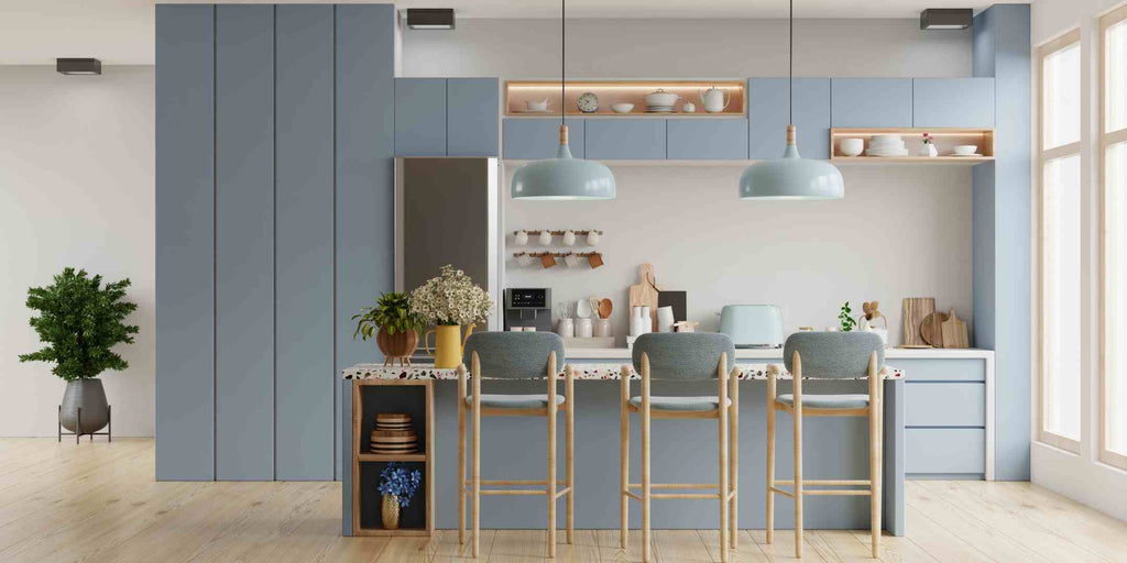 Image illustrating home renovation concepts focused on creating ideal low-light interiors, specifically highlighting the best paint colors for low-light HDB interiors. Showcases a bluish-grey kitchen with a combination of light brown and white accents, creating a cool-toned palette that enhances the perception of light and adds a contemporary touch to the space
