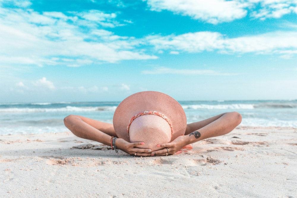A woman wearing a sunhat lying on the sand