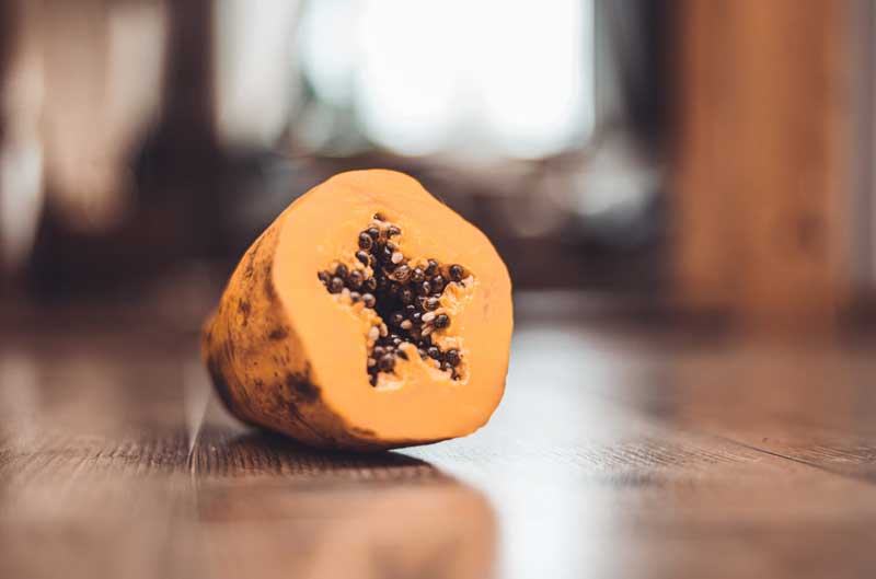 close up on half cut papaya on the wooden surface 