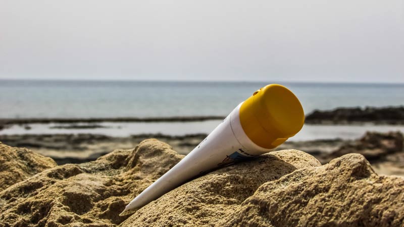 Unknown brand tube of sunscreen laying on the beach sand 
