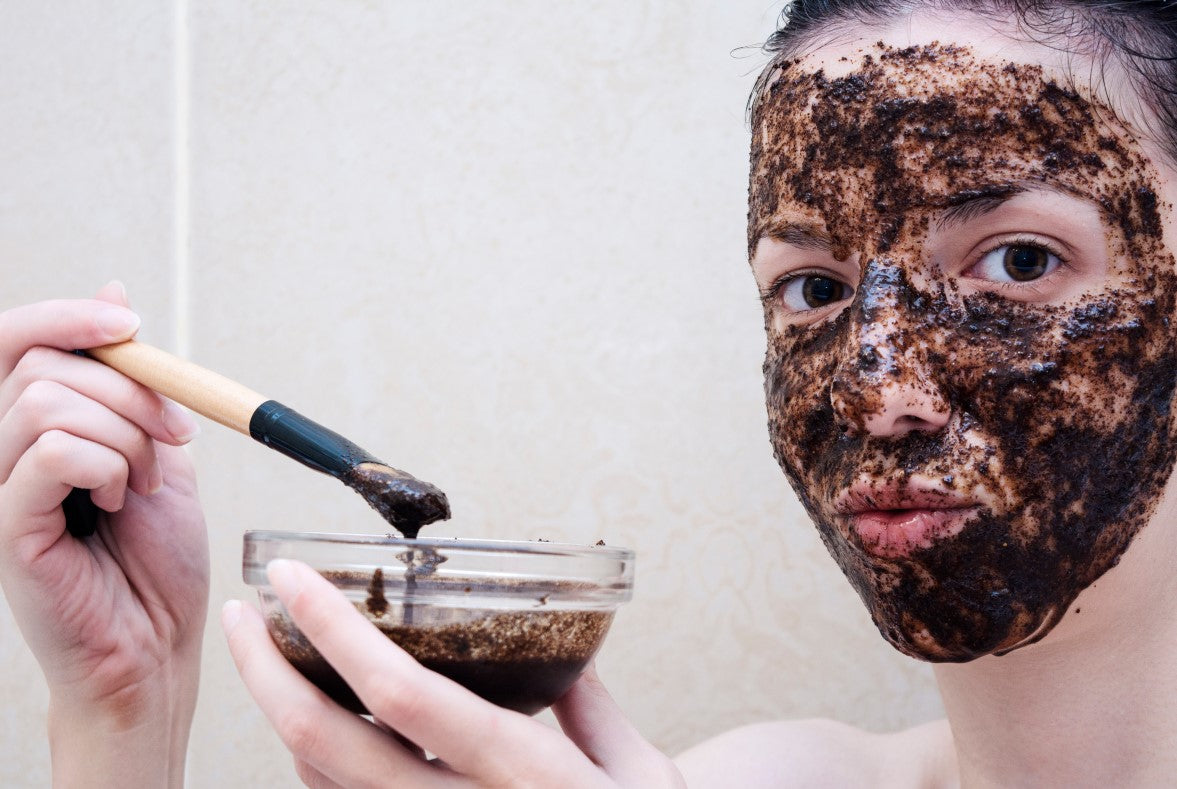 young woman applying facial scrub on her face