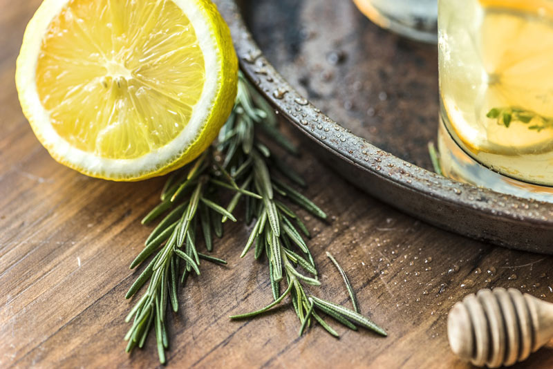 Composition of half lemon, rosemary and glass of lemonade 