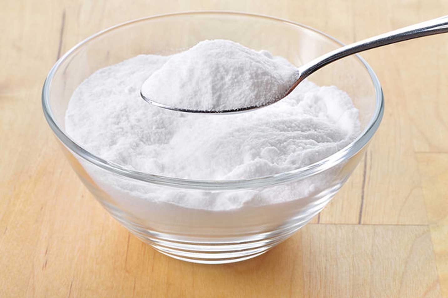 baking soda close-up in glass bowl with spoon inside