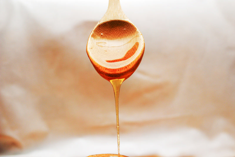 Honey flowing down of the wooden spoon